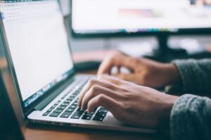 A person typing on a computer for online learning